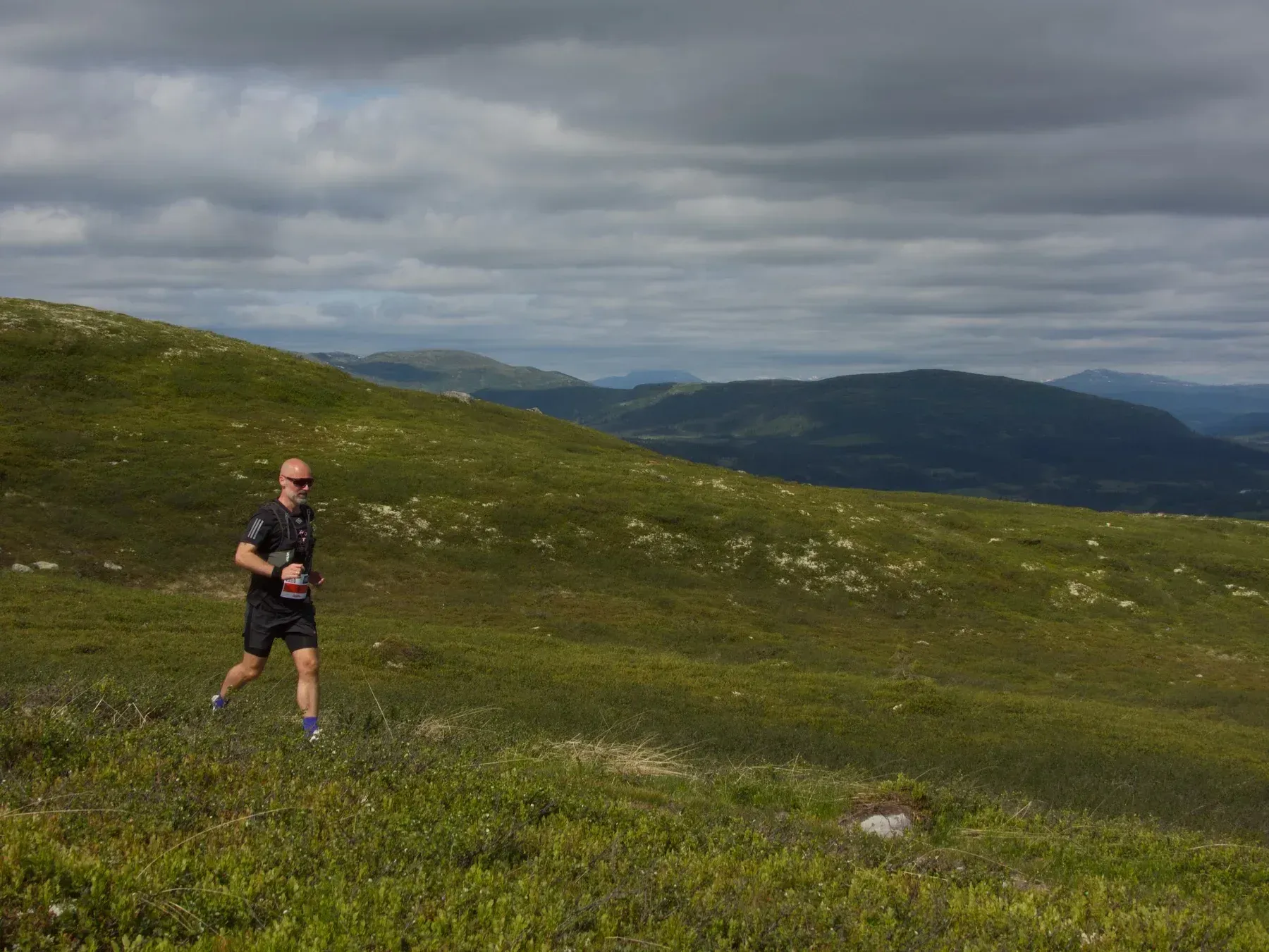 Løper i svart på vei langs en smal sti i fjellsiden.
