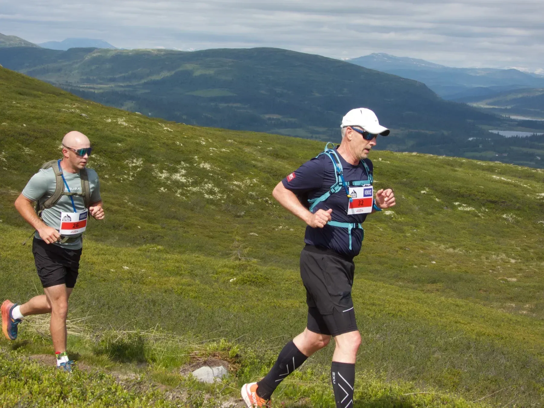 To løpere med startnummer passerer over fjellvidda.