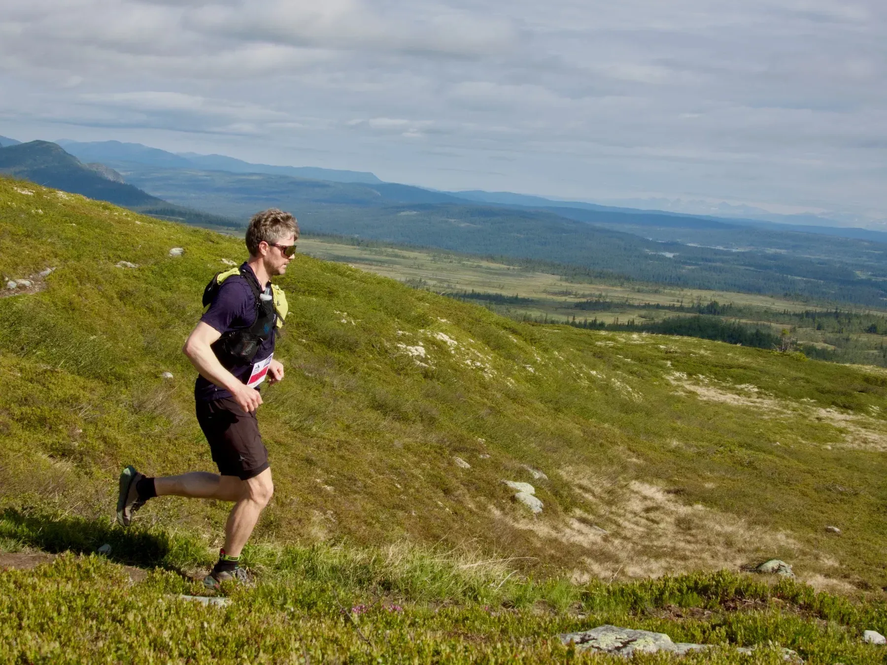Løper i svart på sti med utsikt over dalen.