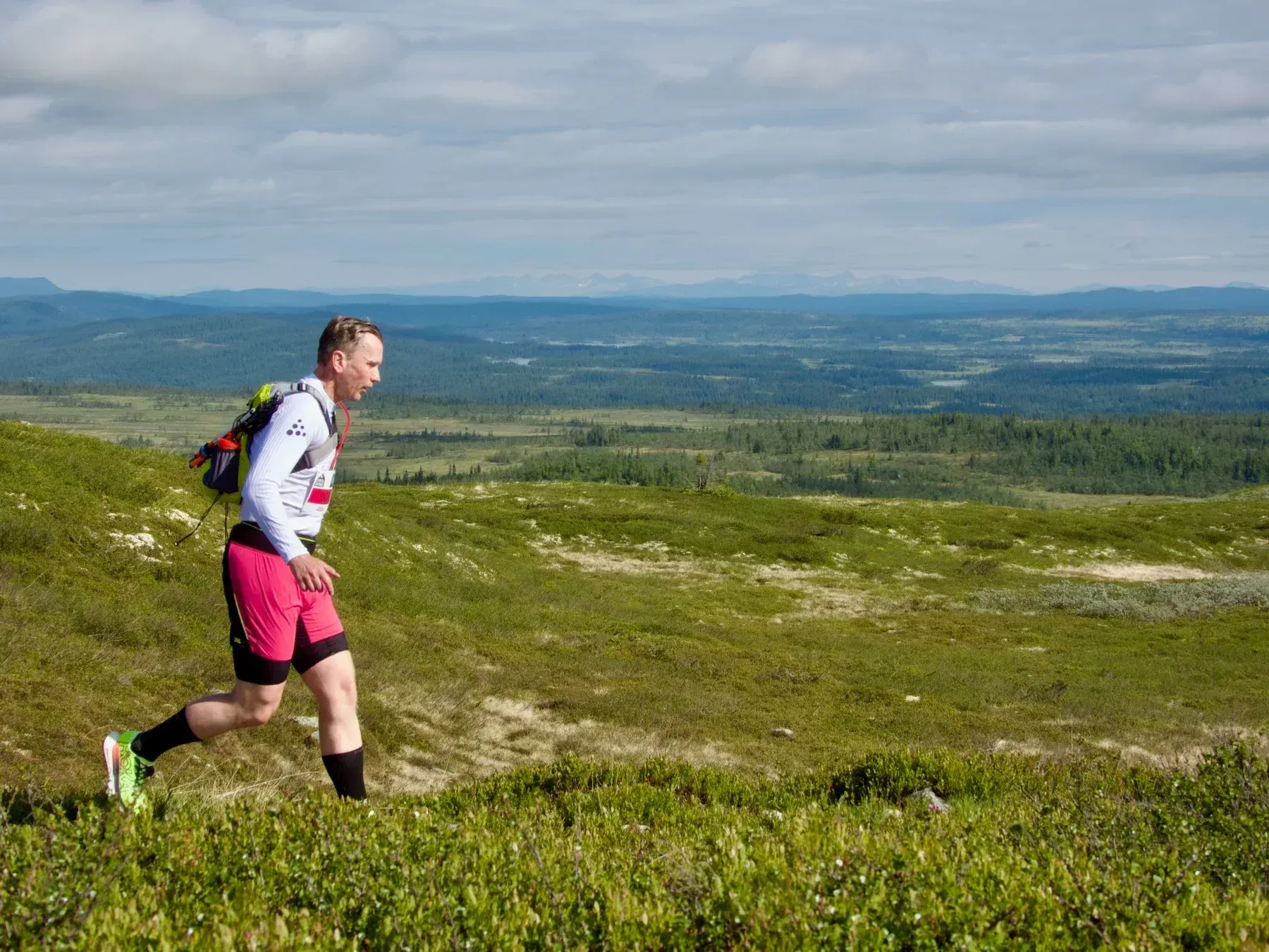 Løper med rosa shorts og hvit jakke langs fjellsiden.