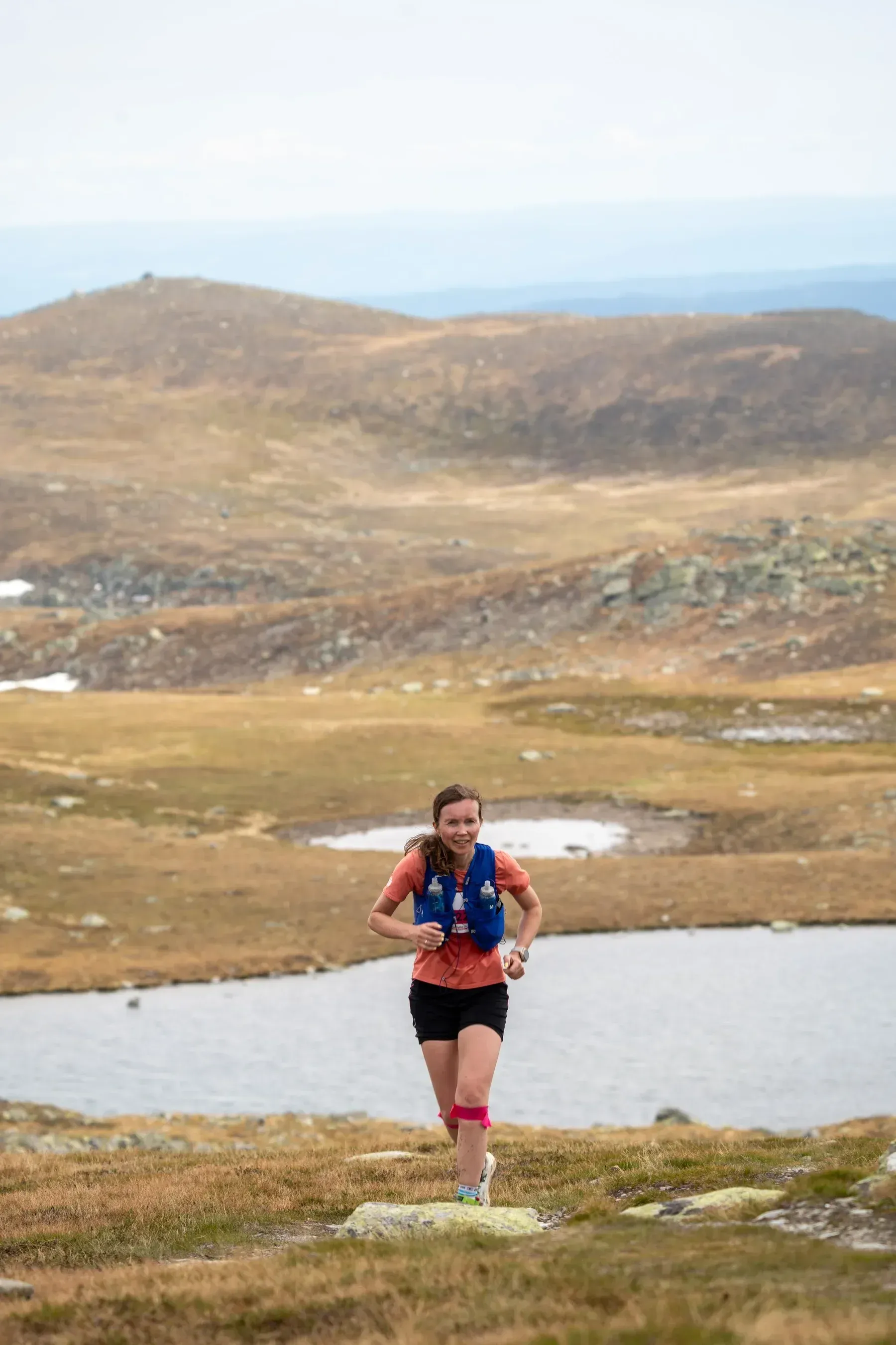 Løper foran et fjellvann og brune fjellsider.