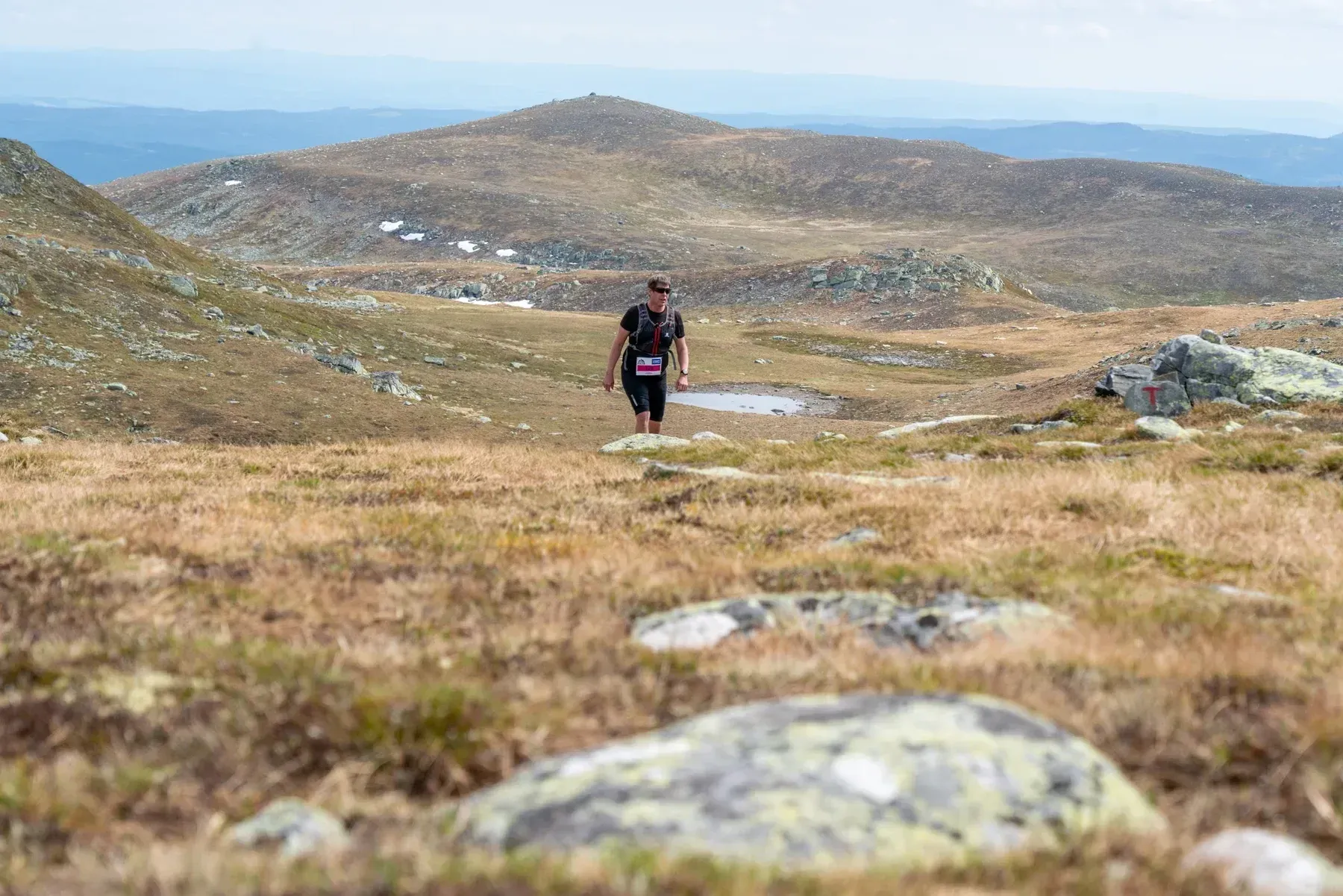 Løper på en smal sti gjennom åpent fjellandskap.